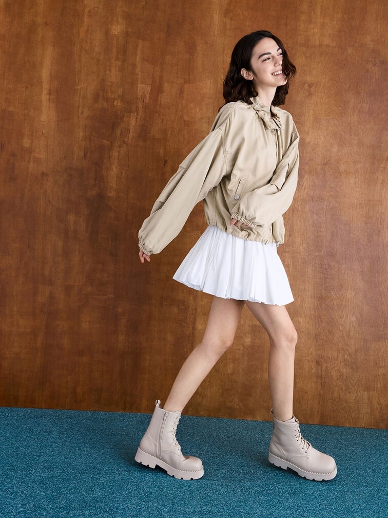 Beige lace-up ankle boots styled with a crisp white pleated mini skirt.