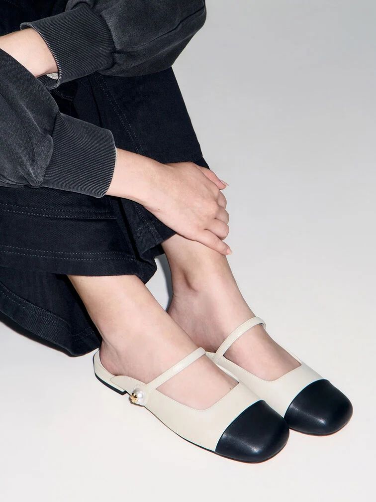 Mules plates à bout rond en noir et blanc, idéales pour un look décontracté au quotidien. 