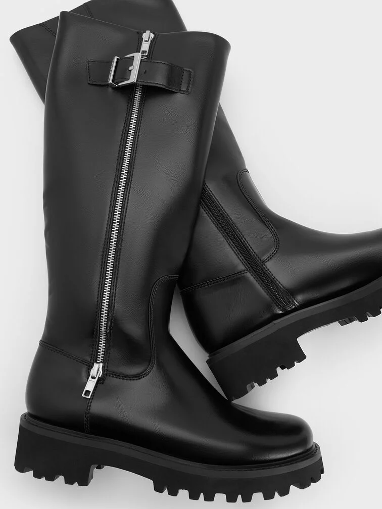 Botas pretas de cano alto com sola tratorada robusta, biqueira redonda e detalhe de fecho com fivela no cano.