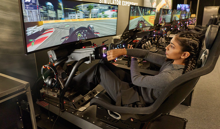 Kareen Kaur enjoying a racing simulator at The F1® Exhibition Singapore - CHARLES & KEITH